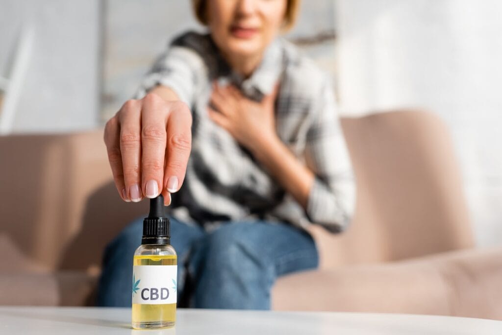 Eine Frau, die CBD-Öl einnimmt, symbolisiert die Wirkung von CBD auf den menschlichen Körper.