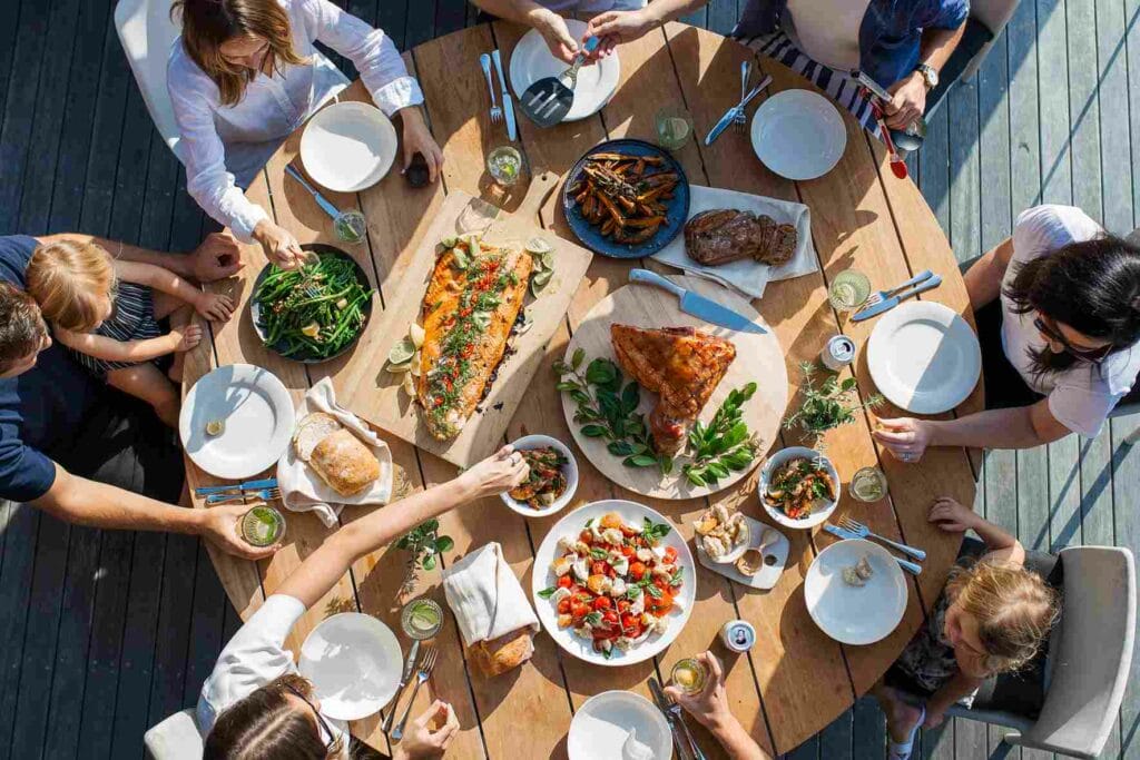 Mehrere Personen bei einer geselligen Mahlzeit mit einem Tisch voller Teller mit buntem Essen