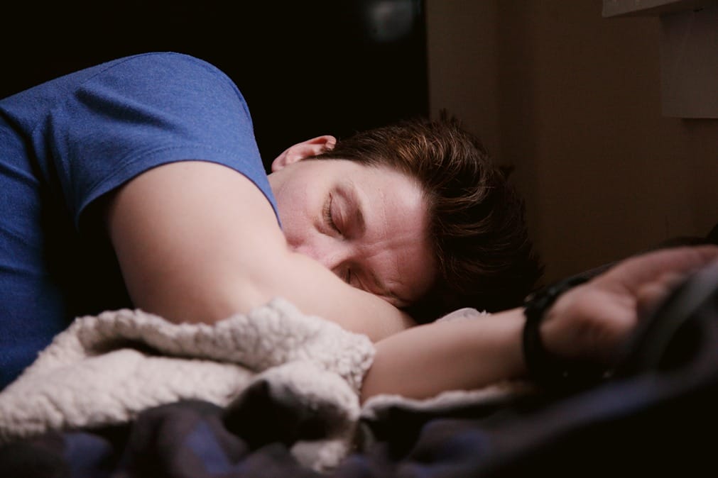 Ein Mann schläft in einem Bett, das die Nebenwirkungen von CBD symbolisiert.