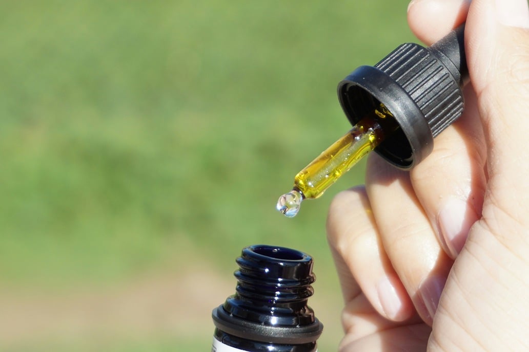 Gouttes d’huile de CBD en cours d’utilisation sous la langue, méthode sublinguale illustrée pour une absorption rapide